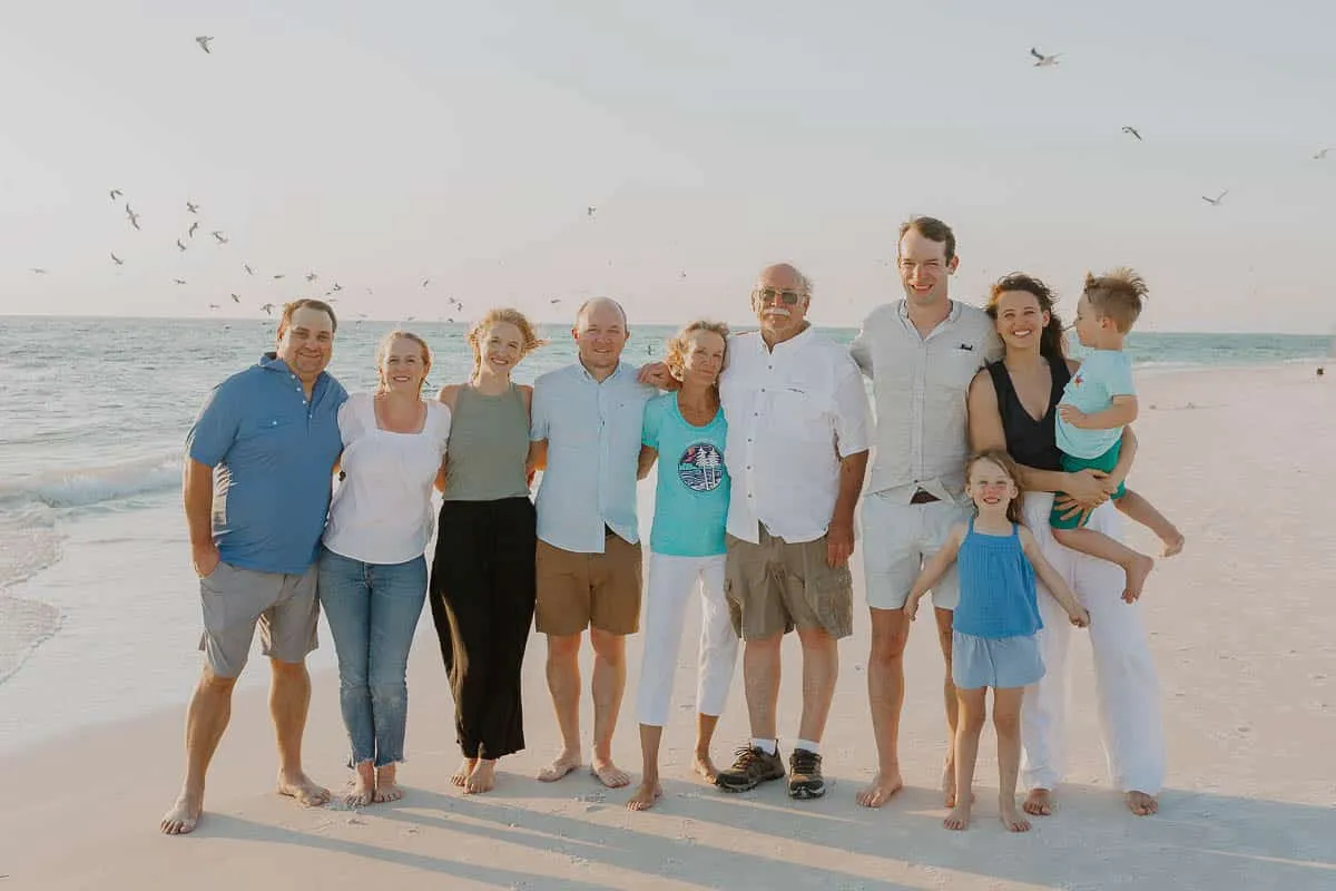 Three generations of a family standing together on the beach at sunset
