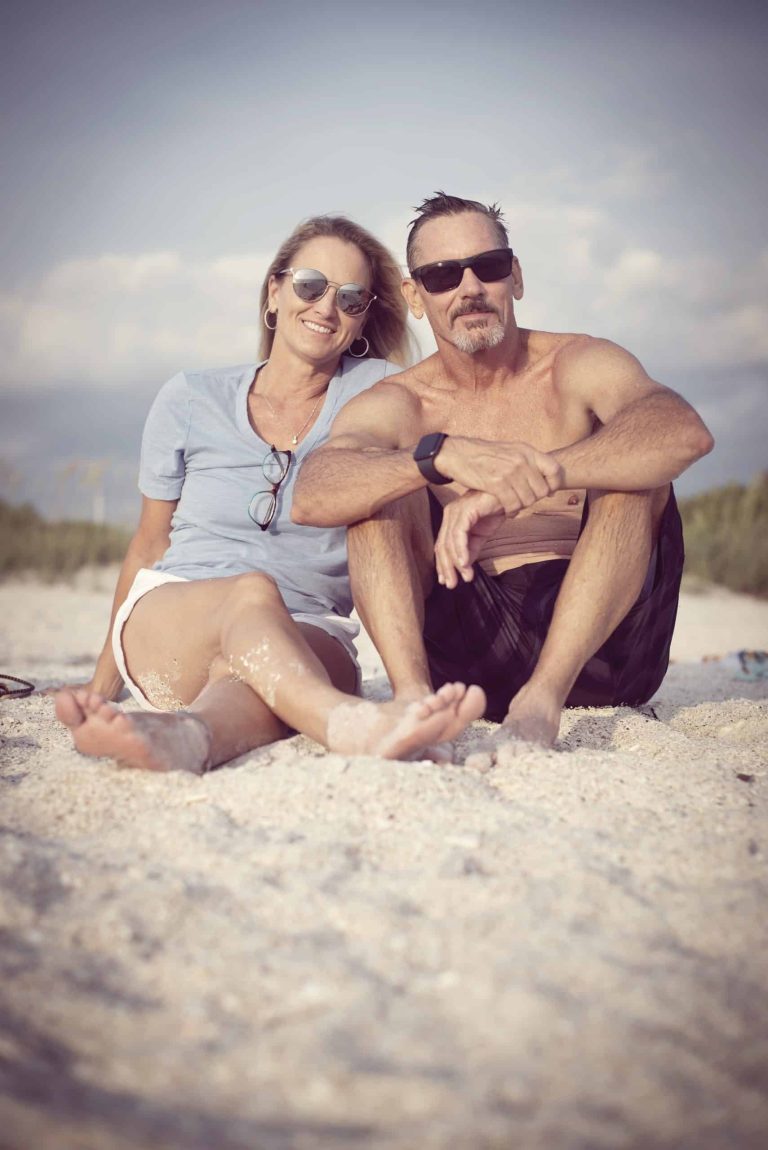 Husband and Wife sitting on beach scaled 1